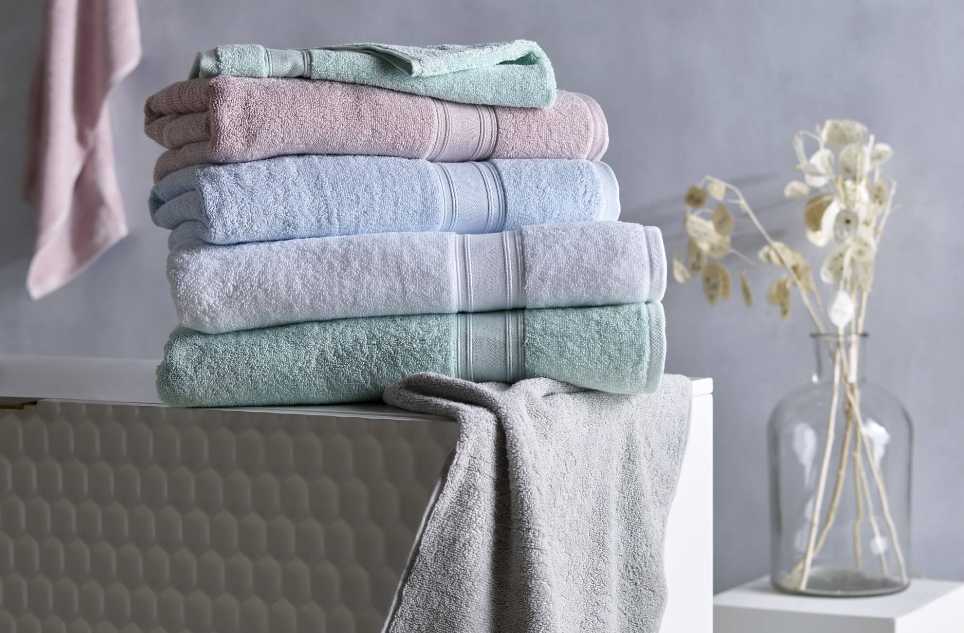 Pastel Coloured KOO Bath Towels Folded & Stacked In A Bathroom